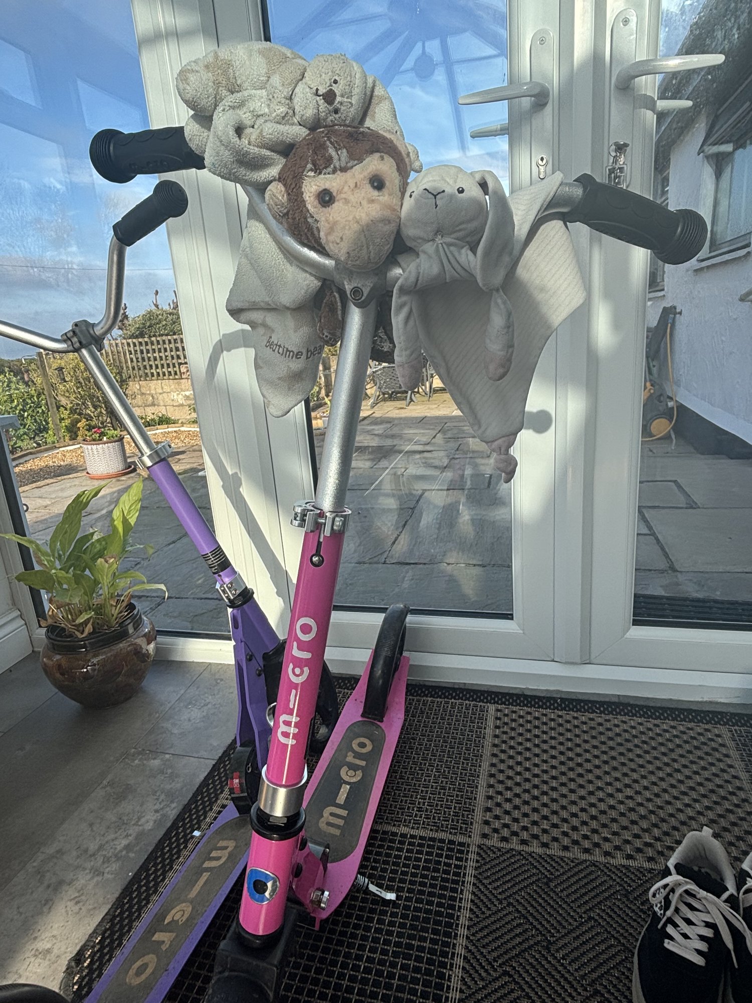Softy, Bear and Bunny tucked into the handlebars of a pink scooter