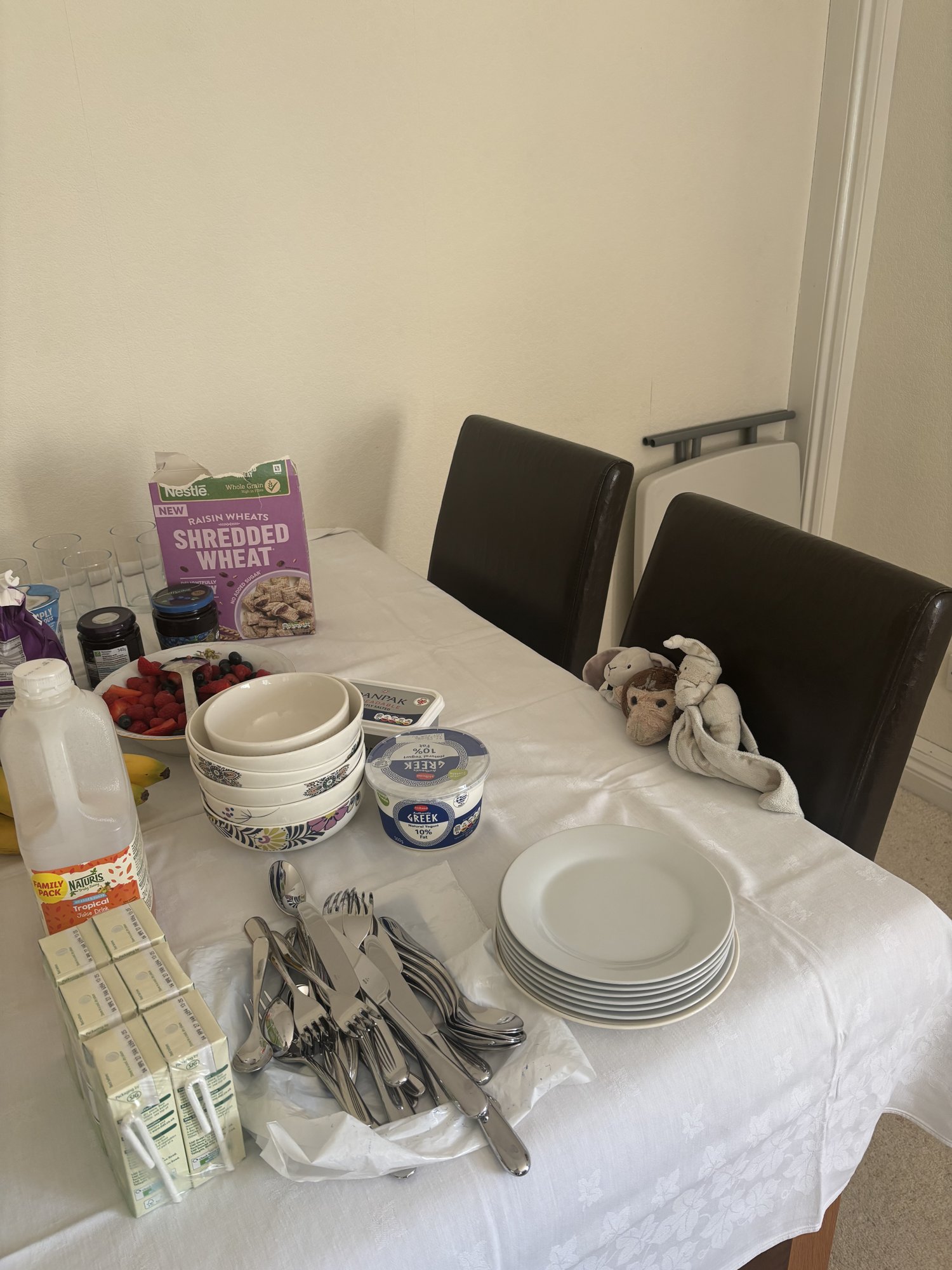 Breakfast spread with cereal, berries and yogurt, Softy, Bear and Bunny watching from a chair